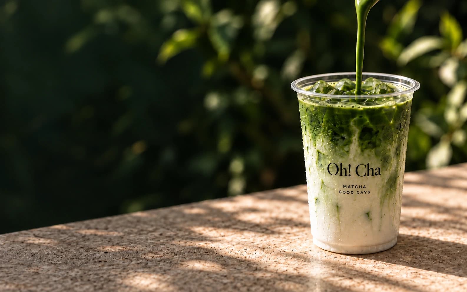 Matcha pouring into an Oh! Cha takeaway cup in warm light